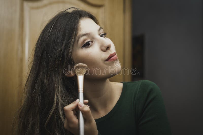 Красивый молодой женщины, подавшие макияж в зеркало. стоковые фотографии rf
