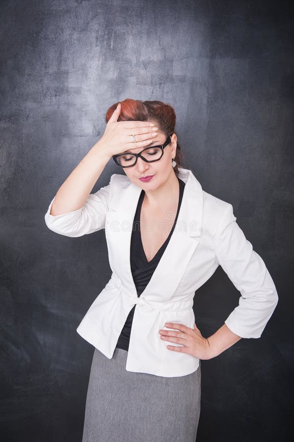 Beautiful teacher with headache on the chalkboard blackboard background. Beautiful teacher with headache on the chalkboard blackboard background