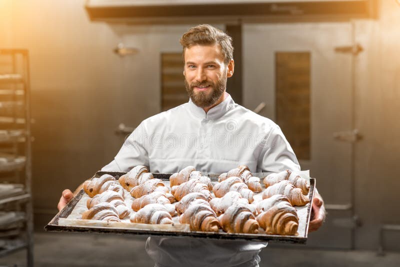 Красивый хлебопек держа поднос полный свеже испеченных croisants стоковые фотографии rf Красивый хлебопек держа поднос полный свеже испеченных croisants стоковые фотографии rf