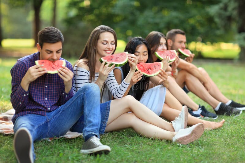 5 красивых молодые люди есть сочный зрелый арбуз внешний стоковые изображения rf