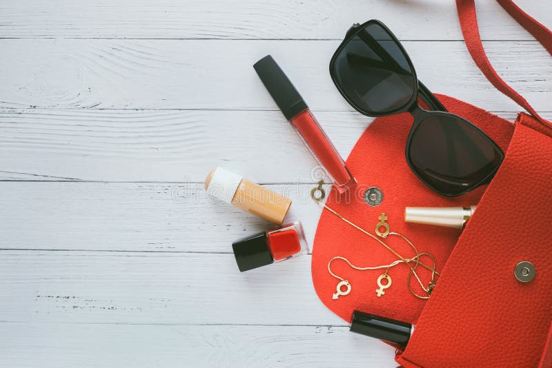 Концепция моды Красная сумка, женские вещи, косметические продукты, sunglass, серьги на деревянной предпосылке с copyspace E стоковое изображение rf Концепция моды Красная сумка, женские вещи, косметические продукты, sunglass, серьги на деревянной предпосылке с copyspace E стоковое изображение rf