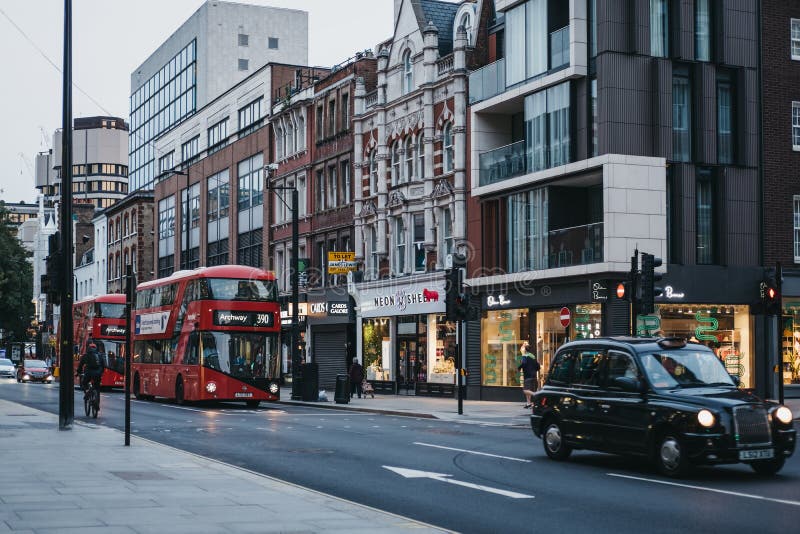 Красные двухэтажные автобусы и автомобили на Tottenham Court Road, London, UK, вечером стоковое изображение rf Красные двухэтажные автобусы и автомобили на Tottenham Court Road, London, UK, вечером стоковое изображение rf
