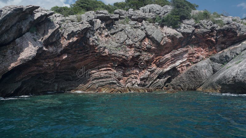 Красные камни кораллы над голубой водой Адриатического моря в Черногории стоковое изображение