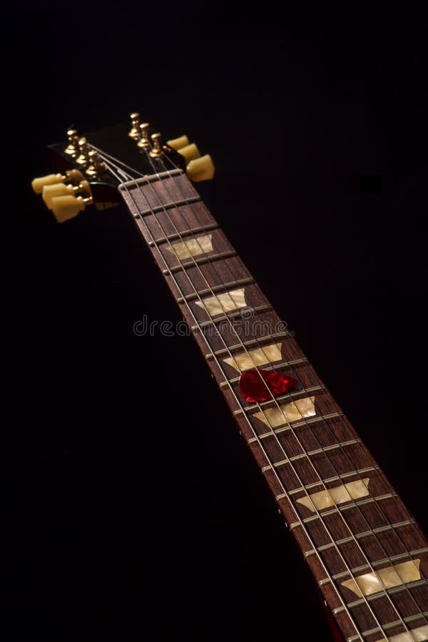 Красный выбор гитары на fingerboard и темноте стоковое фото rf Красный выбор гитары на fingerboard и темноте стоковое фото rf