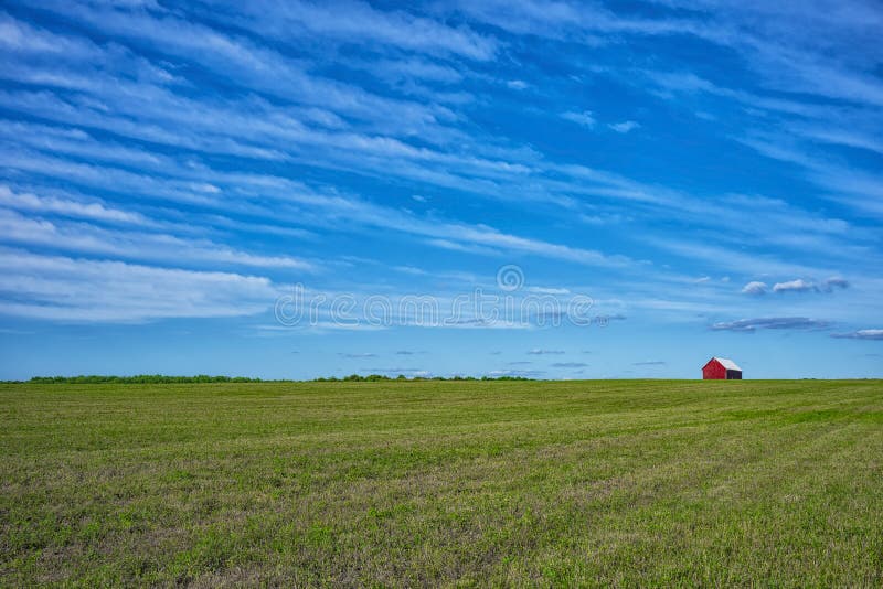 A red barn on the horizon of an open field at a farm on a sunny day in New York State. A red barn on the horizon of an open field at a farm on a sunny day in New York State