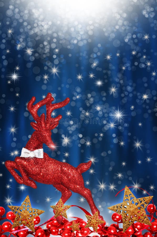 A brightly colored sparkling red reindeer ornament on a pretty blue background with stars and falling dots or snow. Golden stars decorate with red holly berries. A brightly colored sparkling red reindeer ornament on a pretty blue background with stars and falling dots or snow. Golden stars decorate with red holly berries.