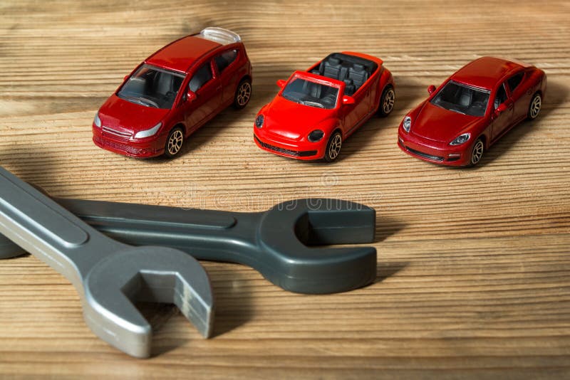 3 красных автомобили игрушки и гаечного ключа игрушки на деревянной предпосылке стоковые фото 3 красных автомобили игрушки и гаечного ключа игрушки на деревянной предпосылке стоковые фото