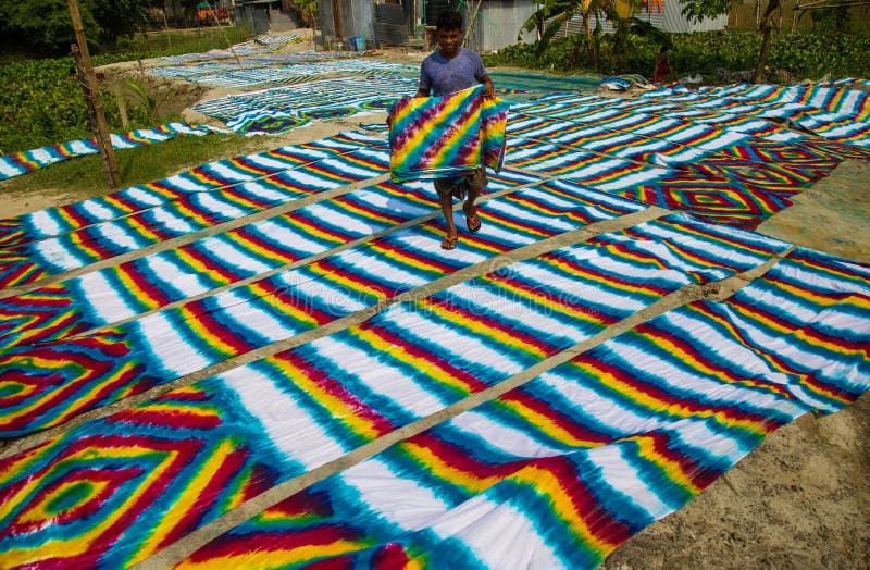 Waves of every color swaying in the wind , and a sweet scent of freshly cut fabric everywhere. It seems the waves of color extended towards horizon. This scene is from Narayanganj's Araihajar Banti, Rupganj's Noagaon and Chanpara villages.A village which once was surrounded by scarcity, its children could not go to school as their parents were unable to pay the fees, now changed the scenario up side down and become a role model for the whole country. Now the families of these villages associated with batik business are earning Tk 2,160 crores annually.Banti village is only 32 km away from Dhaka. All those three villages including Banti are now famous for batik. Batik cloths of three villages are sold in Banti Bazar. Abdul Hai Bhuiyan, President of Banti Bazaar Traders Association, said that batik business started in this market in 1981. At present it has turned into a hub. There are 22 small and big markets on both sides of this hub. There are almost 2500 shops in these markets. Right now 1,500 shops are in operation. The rest of the shops will also open before the next holy month of Ramadan and Pahela Baisakh. Each of the 1,500 shops sell an average of Tk 40,000 worth of batik goods per day. According to that, there is a business of 180 crore rupees per month. And the annual business is 2 thousand 160 crore Taka.From dawn to dusk, the men and women of these villages are busy making batik. As far as the eye can see, cloths painted in various traditional designs are seen hanging on ropes. Residents of the village are dyeing clothes in the yard, side roads, land or open fields, some are blocking, others are drying wet clothes in the sun. Waves of every color swaying in the wind , and a sweet scent of freshly cut fabric everywhere. It seems the waves of color extended towards horizon. This scene is from Narayanganj's Araihajar Banti, Rupganj's Noagaon and Chanpara villages.A village which once was surrounded by scarcity, its children could not go to school as their parents were unable to pay the fees, now changed the scenario up side down and become a role model for the whole country. Now the families of these villages associated with batik business are earning Tk 2,160 crores annually.Banti village is only 32 km away from Dhaka. All those three villages including Banti are now famous for batik. Batik cloths of three villages are sold in Banti Bazar. Abdul Hai Bhuiyan, President of Banti Bazaar Traders Association, said that batik business started in this market in 1981. At present it has turned into a hub. There are 22 small and big markets on both sides of this hub. There are almost 2500 shops in these markets. Right now 1,500 shops are in operation. The rest of the shops will also open before the next holy month of Ramadan and Pahela Baisakh. Each of the 1,500 shops sell an average of Tk 40,000 worth of batik goods per day. According to that, there is a business of 180 crore rupees per month. And the annual business is 2 thousand 160 crore Taka.From dawn to dusk, the men and women of these villages are busy making batik. As far as the eye can see, cloths painted in various traditional designs are seen hanging on ropes. Residents of the village are dyeing clothes in the yard, side roads, land or open fields, some are blocking, others are drying wet clothes in the sun.