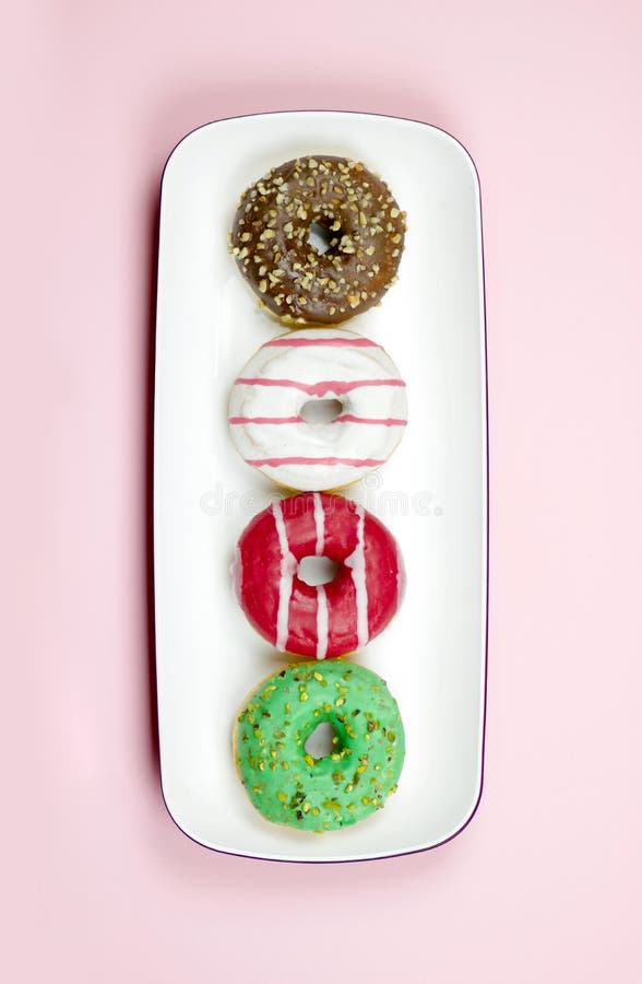 4 красочных donuts на подносе изолированном на backgroun света розовом стоковое фото rf