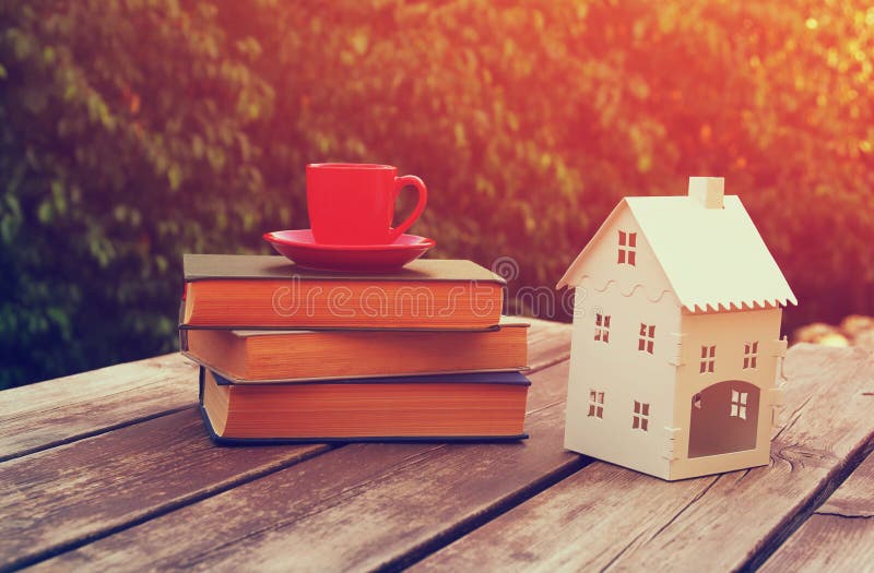Кружка и книга кофейной чашки над деревянным столом outdoors, на времени после полудня модель небольшого дома над деревянным стол стоковые фото Кружка и книга кофейной чашки над деревянным столом outdoors, на времени после полудня модель небольшого дома над деревянным стол стоковые фото