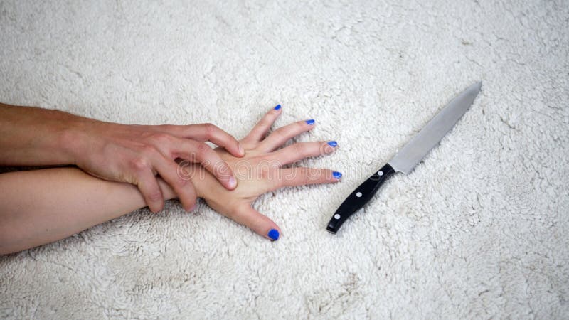 Hand of woman trying to grab a knife while being attacked by man. Hand of woman trying to grab a knife while being attacked by man