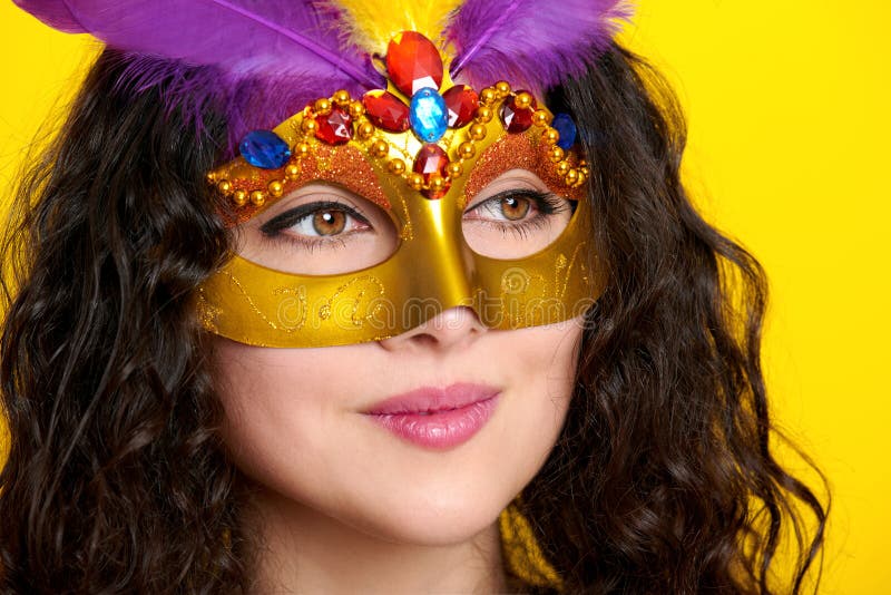 Крупный план стороны женщины в маске masquerade масленицы с пером, красивым портретом девушки на желтой предпосылке цвета, длинно стоковое фото Крупный план стороны женщины в маске masquerade масленицы с пером, красивым портретом девушки на желтой предпосылке цвета, длинно стоковое фото
