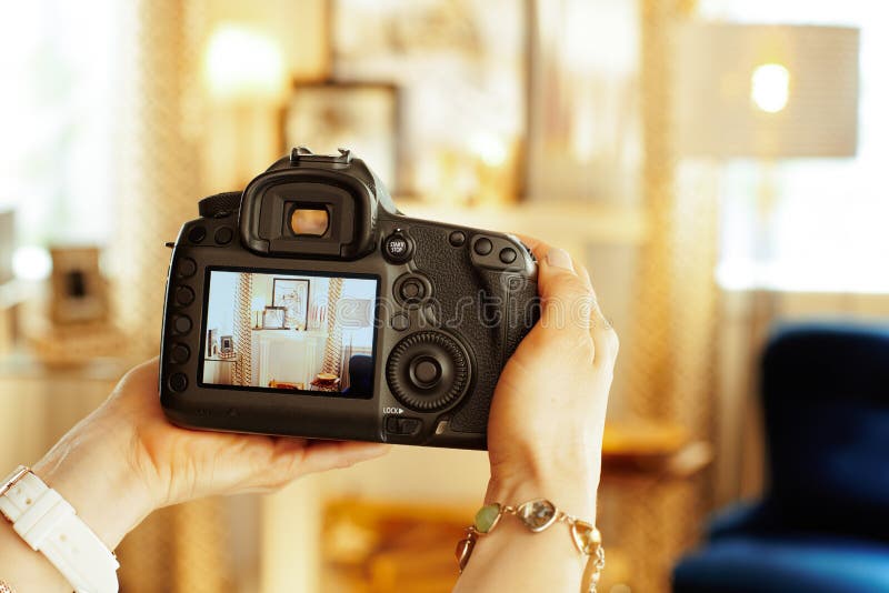 Крупный план на камере DSLR в руке женского внутреннего фотографа стоковая фотография Крупный план на камере DSLR в руке женского внутреннего фотографа стоковая фотография