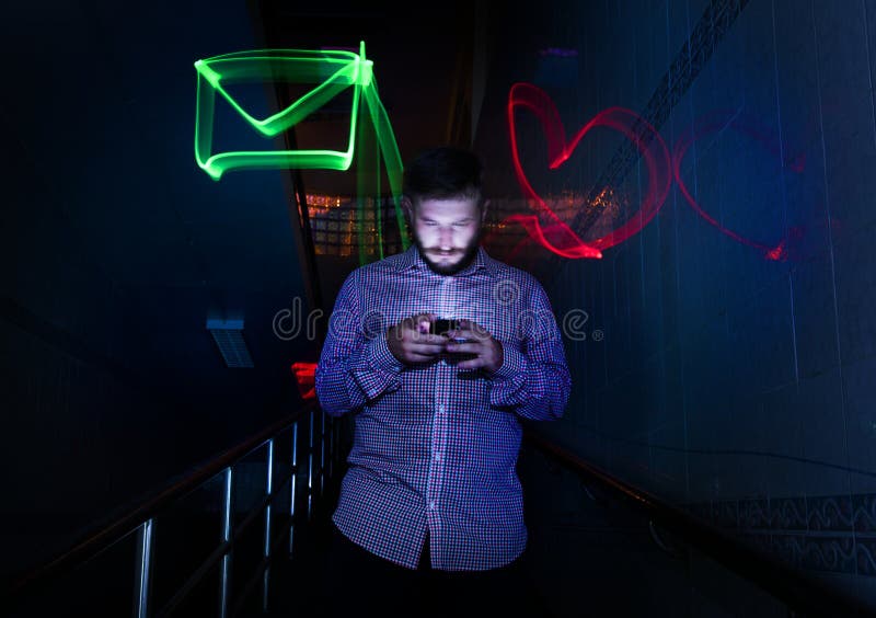 Крупный план человека используя nighttime мобильного телефона с длинным exposur стоковая фотография rf Крупный план человека используя nighttime мобильного телефона с длинным exposur стоковая фотография rf