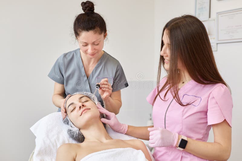 Крытая съемка beautician и ее молодой ассистент снабжая качественное обслуживание клиента их положенный клиент с закрытыми глазам стоковые фото Крытая съемка beautician и ее молодой ассистент снабжая качественное обслуживание клиента их положенный клиент с закрытыми глазам стоковые фото
