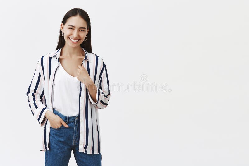 Крытая съемка счастливого успешного молодого женского предпринимателя в striped блузке и джинсах, держащ руку в карманн, усмехаяс стоковая фотография Крытая съемка счастливого успешного молодого женского предпринимателя в striped блузке и джинсах, держащ руку в карманн, усмехаяс стоковая фотография