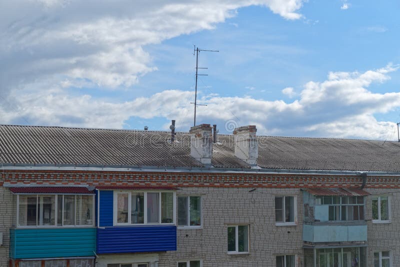 Крыша старого многоквартирного дома против изумительного облачного неба стоковые фотографии rf Крыша старого многоквартирного дома против изумительного облачного неба стоковые фотографии rf