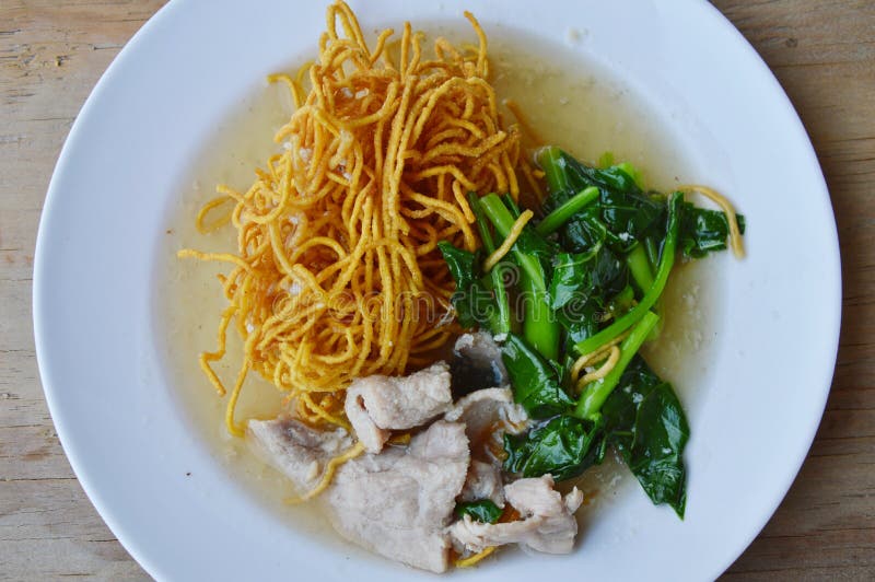 Crispy egg noodle with Chinese kale and pork in gravy sauce on dish. Crispy egg noodle with Chinese kale and pork in gravy sauce on dish