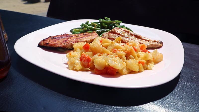 Курица на гриле с макаронами и зелёной фасолью на открытом столе под солнцем видеоматериал