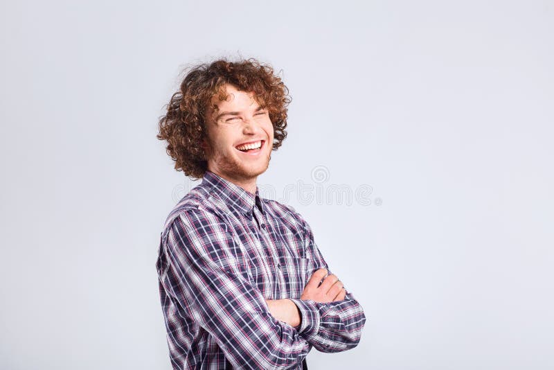 Curly guy smiles with a positive emotion up against a gray background. Curly guy smiles with a positive emotion up against a gray background.