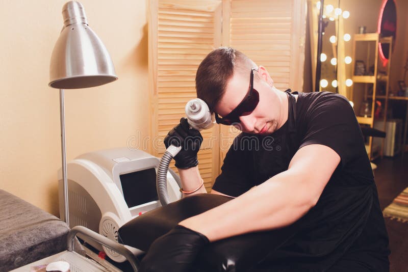 Лазер удаления татуировки Cosmetologist профессиональный в салоне стоковые изображения rf Лазер удаления татуировки Cosmetologist профессиональный в салоне стоковые изображения rf