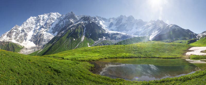 Ландшафт горы Svaneti на день яркого лета солнечный Озеро гор, холмы покрыло зеленую траву на снежных скалистых горах стоковое фото Ландшафт горы Svaneti на день яркого лета солнечный Озеро гор, холмы покрыло зеленую траву на снежных скалистых горах стоковое фото