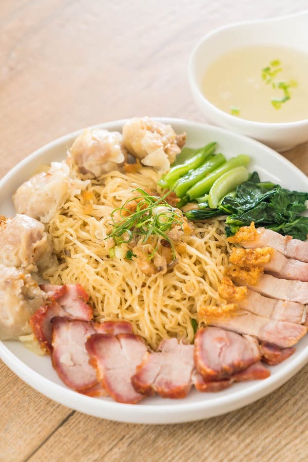 Egg noodle with red roast pork, crispy pork, dumplings, soup and condiments. Egg noodle with red roast pork, crispy pork, dumplings, soup and condiments