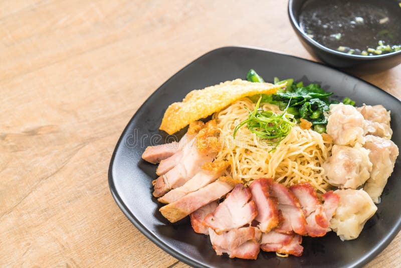 Egg noodle with red roast pork, crispy pork, dumplings, soup and condiments. Egg noodle with red roast pork, crispy pork, dumplings, soup and condiments