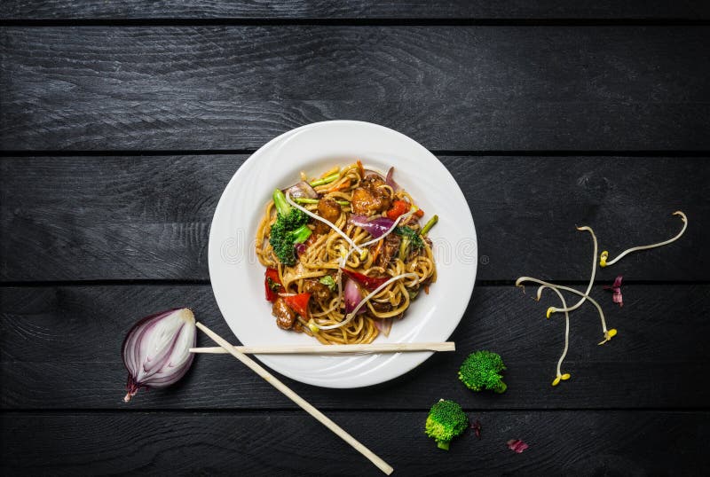 Лапши фрая stir Udon с мясом или цыпленком и овощами в белой плите с палочками стоковая фотография rf Лапши фрая stir Udon с мясом или цыпленком и овощами в белой плите с палочками стоковая фотография rf