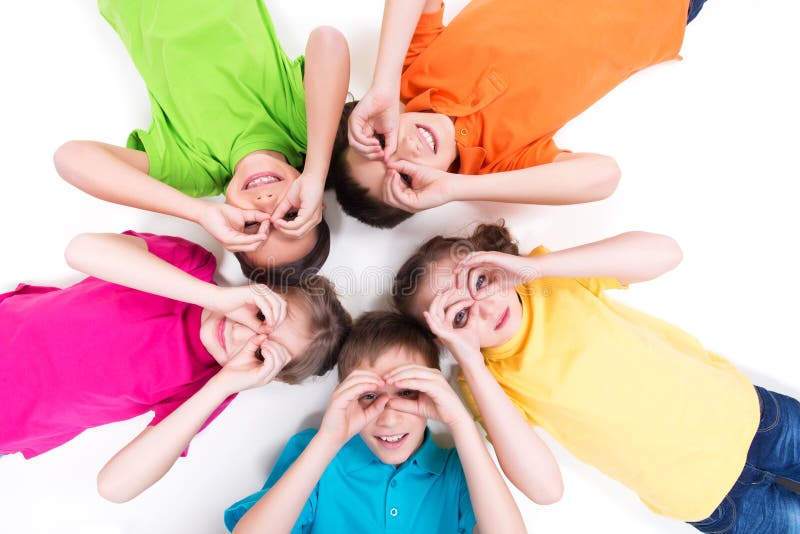 Five happy children lying on the floor in a circle with hands near eyes in bright t-shirts. Top view. Isolated on white. Five happy children lying on the floor in a circle with hands near eyes in bright t-shirts. Top view. Isolated on white.