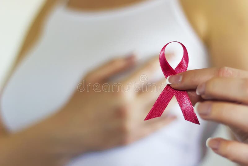 Woman hold pink ribbon for breast cancer awareness. Blurred background. Copy space available. Woman hold pink ribbon for breast cancer awareness. Blurred background. Copy space available.
