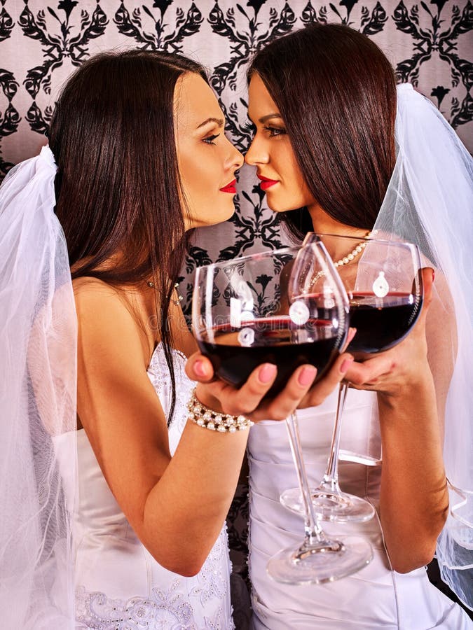 Лесбосские пары в wedding bridal платье целуя и выпивая красное вино стоковые изображения rf Лесбосские пары в wedding bridal платье целуя и выпивая красное вино стоковые изображения rf