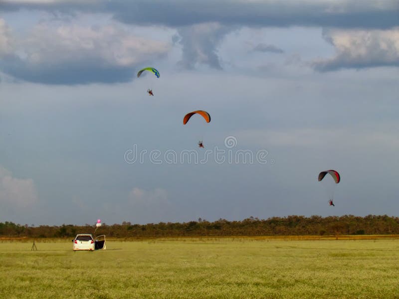 Летание параплана с paramotor над полем белых цветков Белый автомобиль с воздушными шарами связанными к стульям и треноги упорки стоковые изображения rf Летание параплана с paramotor над полем белых цветков Белый автомобиль с воздушными шарами связанными к стульям и треноги упорки стоковые изображения rf