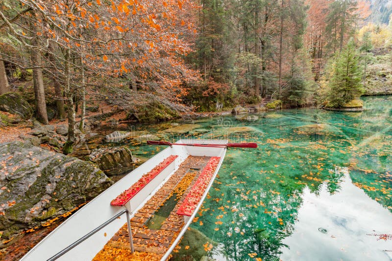 Листья красного цвета и красная шлюпка на природном парке озера Blausee/голубом, Kande стоковая фотография rf Листья красного цвета и красная шлюпка на природном парке озера Blausee/голубом, Kande стоковая фотография rf