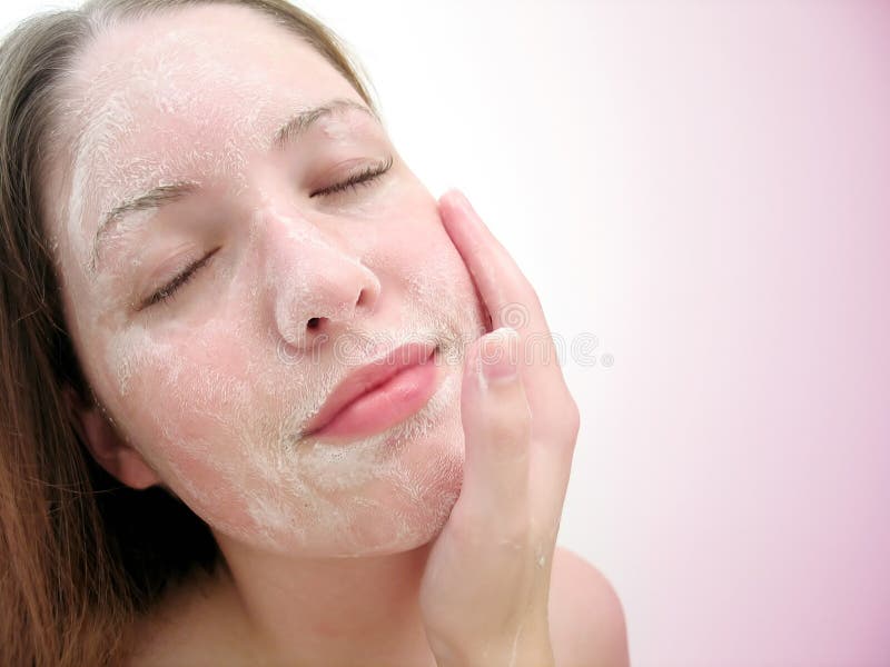 Woman washing her face with soap, eyes closed, small grin. Pink tones. Woman washing her face with soap, eyes closed, small grin. Pink tones.