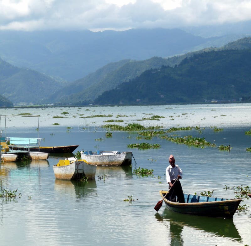 Лодочник на pokhara Непале озера phewa с гор в фоновом режиме стоковая фотография rf