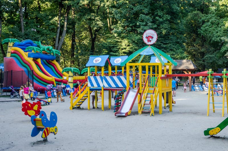 Львов, Украина - 19-ое августа 2015: Спортивная площадка детей с качаниями и раздувной батут в парке атракционов где игра детей стоковое фото rf