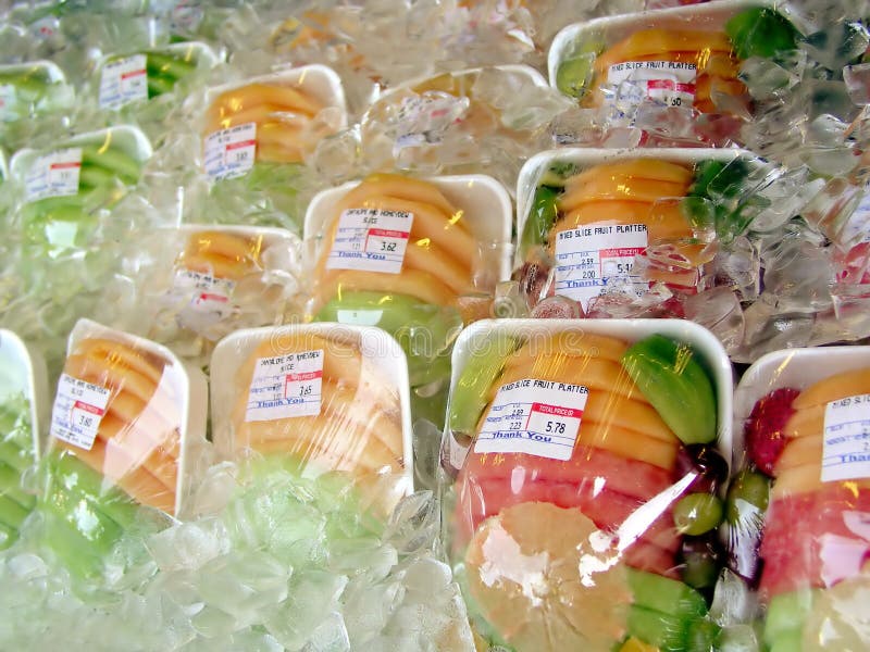 Plastic wrapped fresh fruits on ice on a deli stand. Brightly colored pieces of watermelon, honeydew, cantaloupe, grapefruit, strawberries and kiwi. Plastic wrapped fresh fruits on ice on a deli stand. Brightly colored pieces of watermelon, honeydew, cantaloupe, grapefruit, strawberries and kiwi.