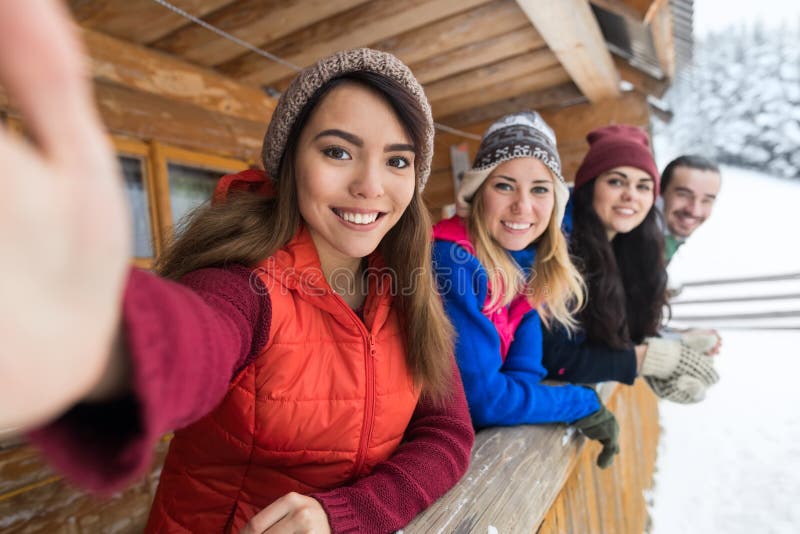 Люди собирают принимать фото Selfie умный телефон деревянный горнолыжный курорт снега зимы террасы загородного дома стоковые изображения rf Люди собирают принимать фото Selfie умный телефон деревянный горнолыжный курорт снега зимы террасы загородного дома стоковые изображения rf