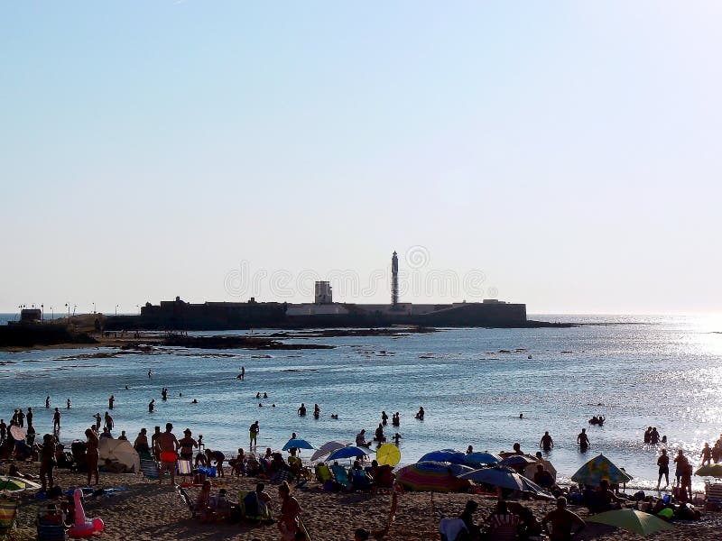 Люди загорая на заходе солнца на пляже Ла Caleta в заливе Кадиса, Андалусии Испания стоковая фотография Люди загорая на заходе солнца на пляже Ла Caleta в заливе Кадиса, Андалусии Испания стоковая фотография