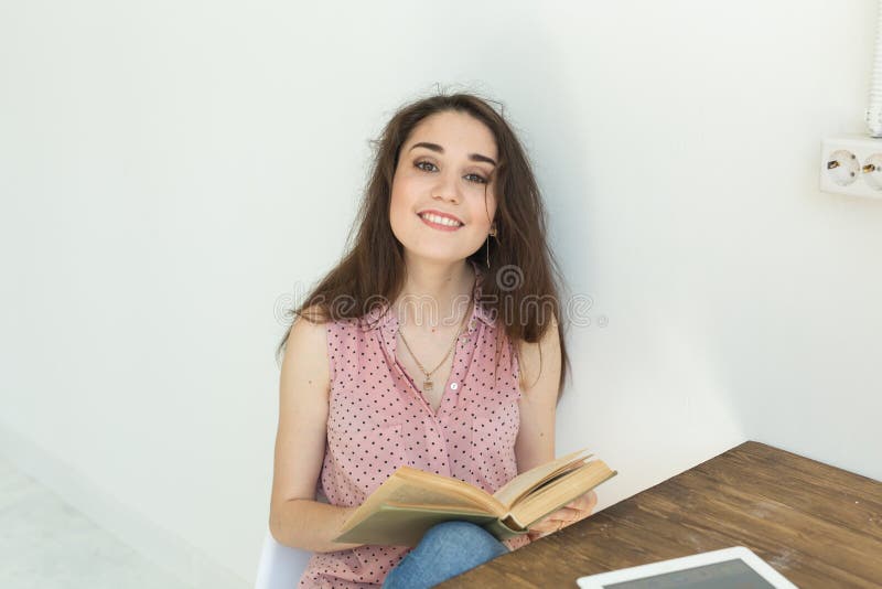 Люди, книги и концепция образования - портрет счастливой студентки сидя с книгой стоковые изображения Люди, книги и концепция образования - портрет счастливой студентки сидя с книгой стоковые изображения