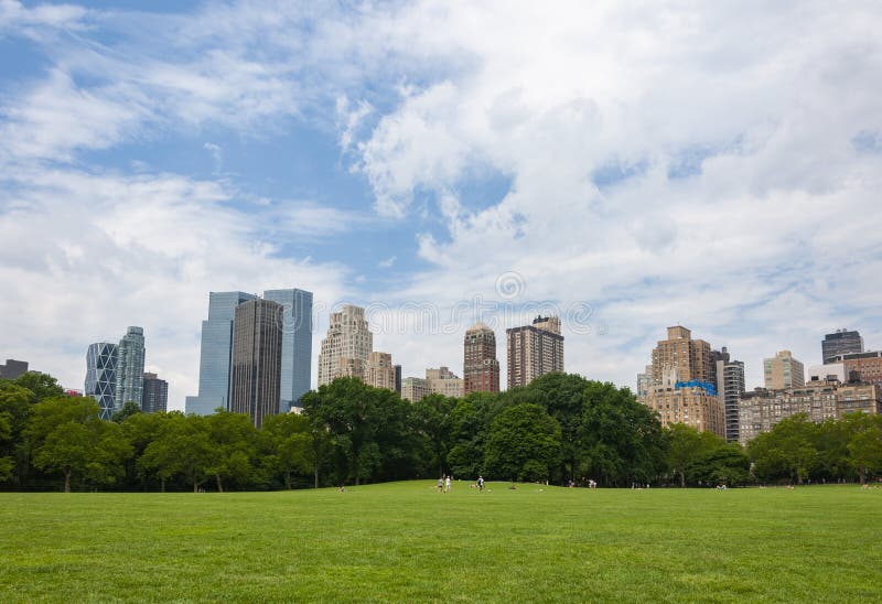 люди ослабляя на Central Park с горизонтом Нью-Йорка на заднем плане, в городе Нью-Йорка, США стоковые фотографии rf люди ослабляя на Central Park с горизонтом Нью-Йорка на заднем плане, в городе Нью-Йорка, США стоковые фотографии rf