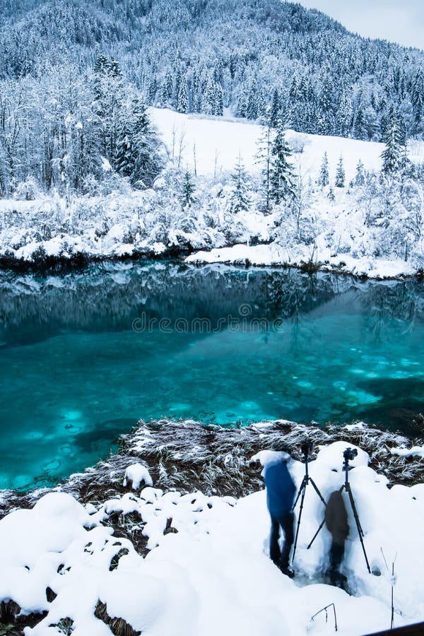 Люди принимая фото на красивом изумрудно-зеленом zelenci в пейзаже зимы, Kranjska Gora озера, Словении стоковое фото rf Люди принимая фото на красивом изумрудно-зеленом zelenci в пейзаже зимы, Kranjska Gora озера, Словении стоковое фото rf