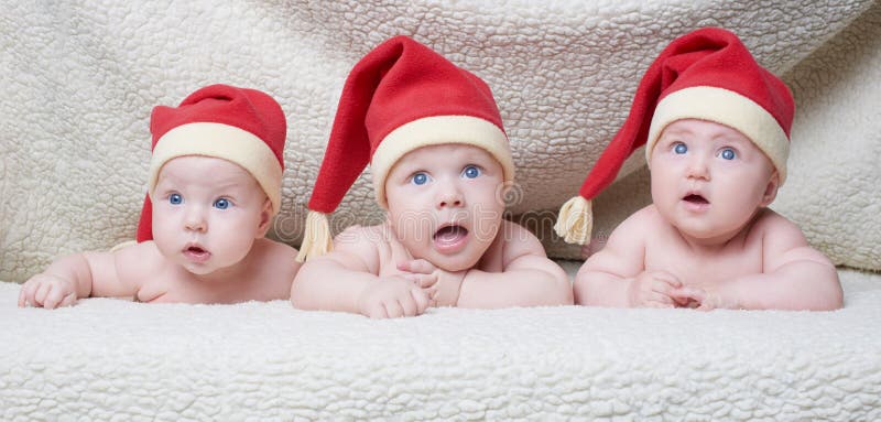 Младенцы с шляпами santa на яркой предпосылке стоковое изображение rf Младенцы с шляпами santa на яркой предпосылке стоковое изображение rf