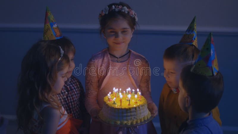 Маленькая девочка дует вне свечи на именнином пироге на партии, последовательности замедленного движения