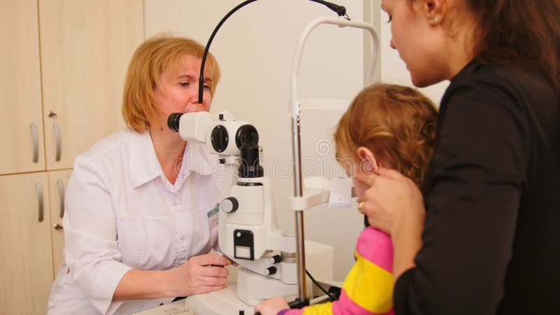 Маленький ребенок на докторе ` s офтальмологии - optometrist проверяет зрение для девушки видеоматериал