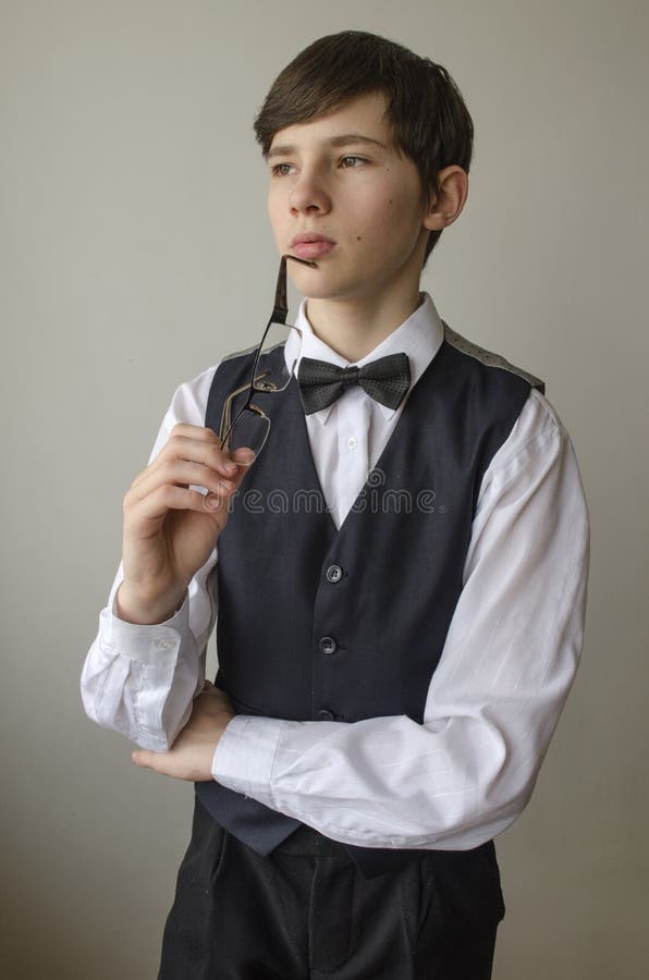 Мальчик подростка с стеклами в руках в белой рубашке и жилете с черной ...