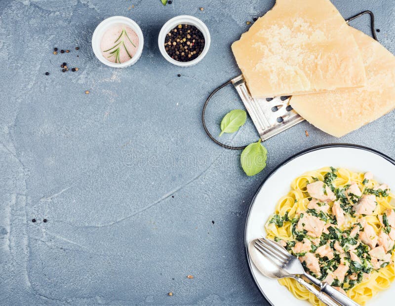 Макаронные изделия Tagliatelle с семгами, шпинатом и сметанообразным соусом, сыр пармесаном над конкретной текстурированной предп стоковые изображения Макаронные изделия Tagliatelle с семгами, шпинатом и сметанообразным соусом, сыр пармесаном над конкретной текстурированной предп стоковые изображения