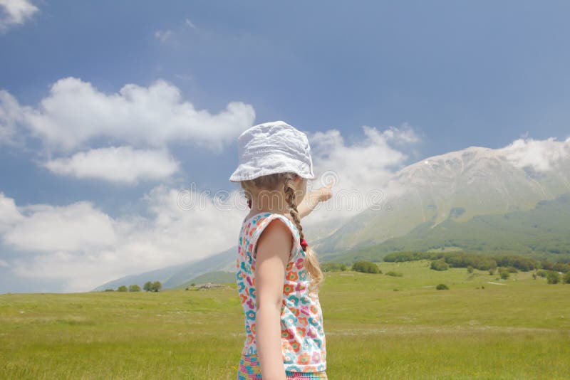 Маленькая девочка в итальянке Apennines зоны Abruzzi указывая на взгляд гребня горы стоковое фото rf Маленькая девочка в итальянке Apennines зоны Abruzzi указывая на взгляд гребня горы стоковое фото rf