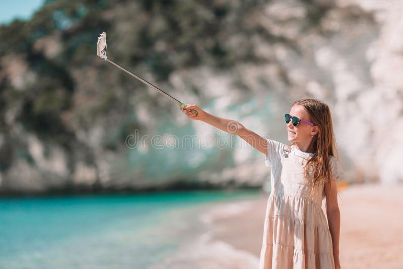 Маленькая девочка принимая selfie ее смартфоном на пляже Ребенк наслаждаясь ее каникулами suumer и делая фото для памяти стоковая фотография